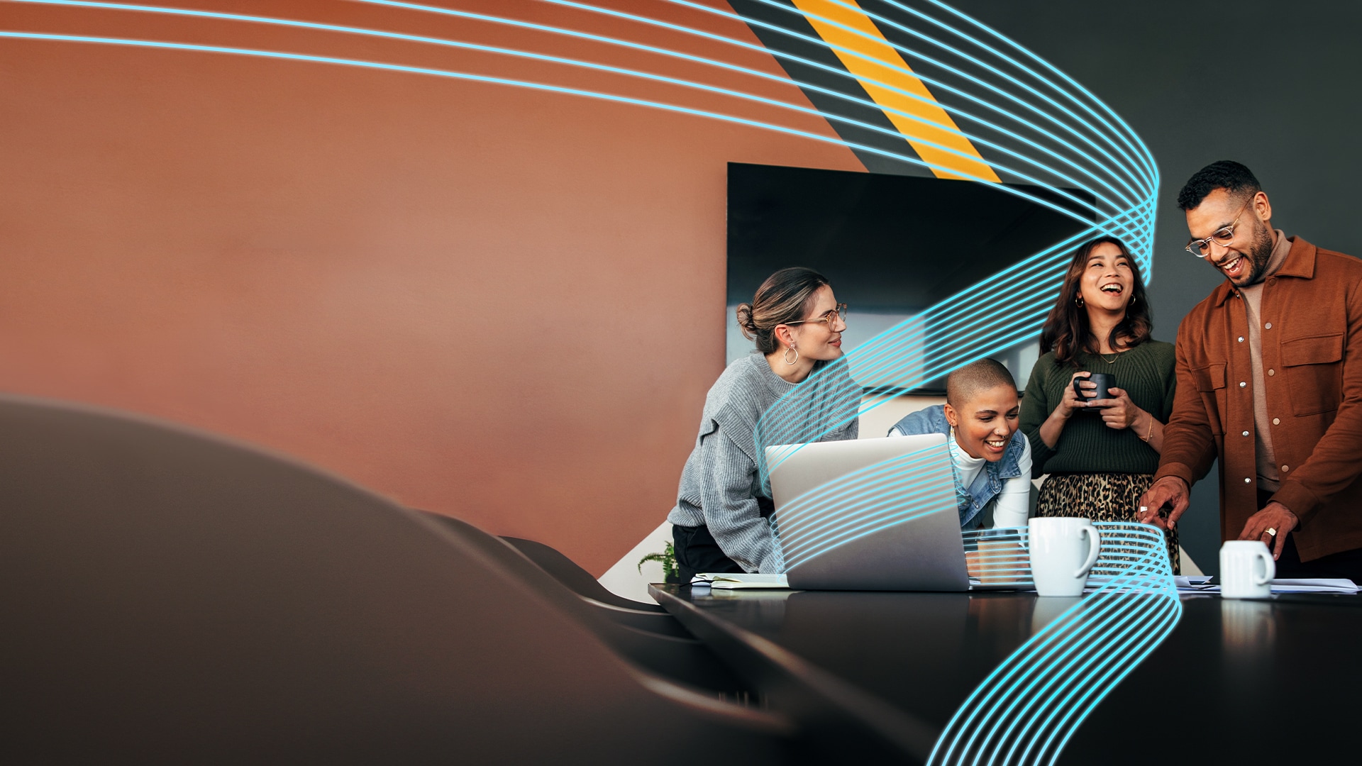 A group of people laughing, drinking coffee and looking at a computer in an office